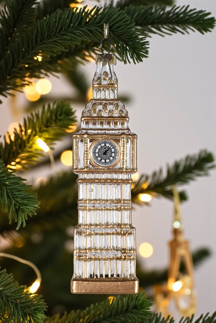 Christmas tree ornament shaped like Big Ben with blurred lights in the background