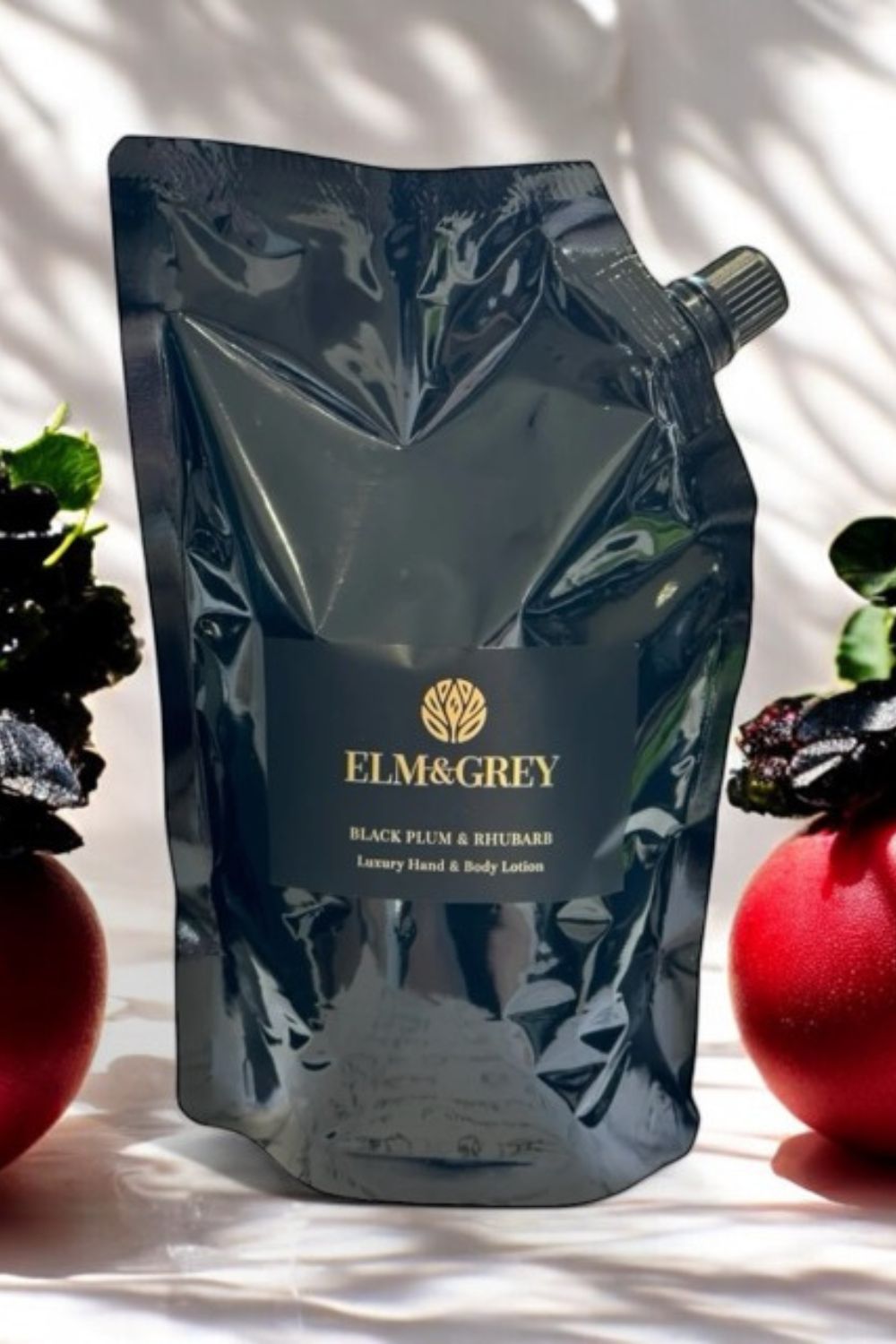ELM&GREY black plum & rhubarb body lotion packaging with fruits in the background
