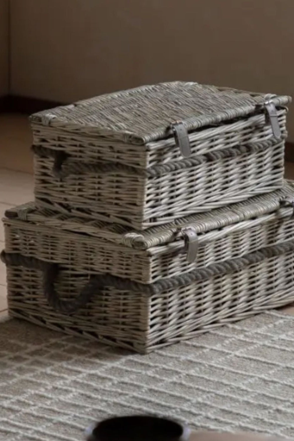 Two woven storage baskets stacked on a textured surface with a neutral background