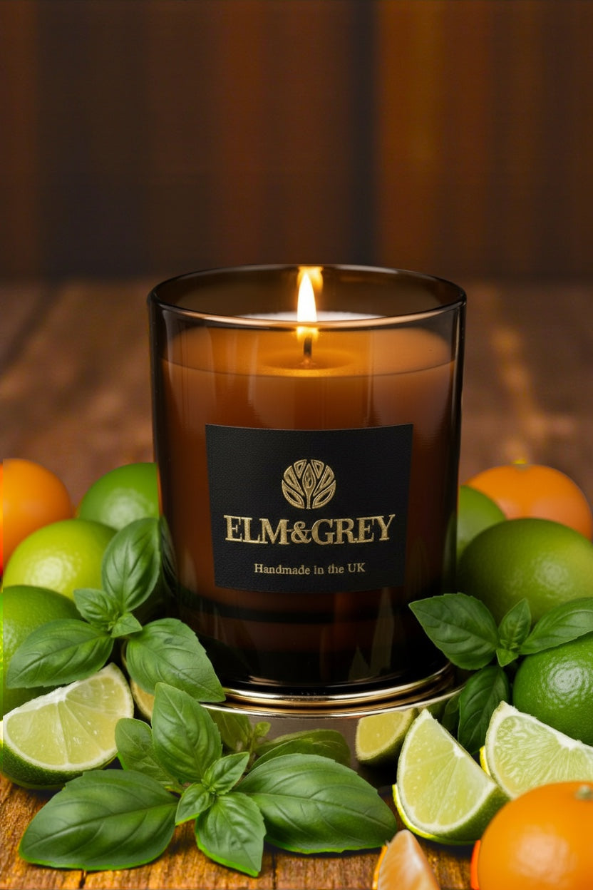 Candle with 'Elm&Grey' label surrounded by citrus fruits on a wooden surface