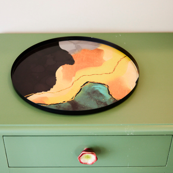 Colourful tray in an abstract design on a green dresser