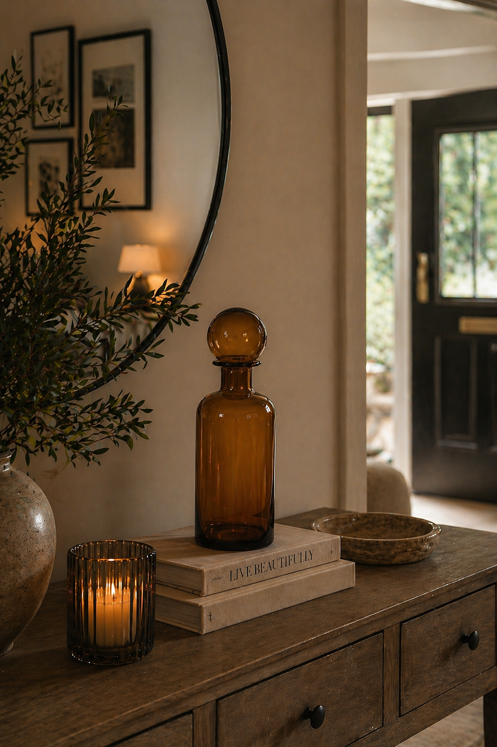Amber glass bottle on a wooden console table with books and a candle, in a home setting.