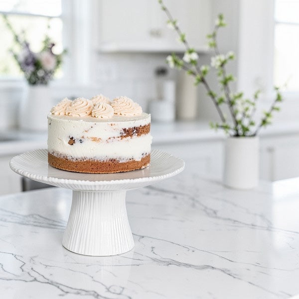 Layered cake on a white cake stand in a kitchen setting