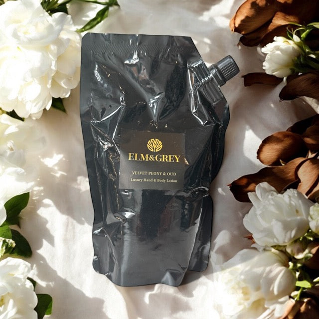 Elm & Grey Velvet Peony & Oud Luxury Hand & Body Lotion 450ml Black Refill Pouch sitting on a surface with White Peonies and Oud  in the background