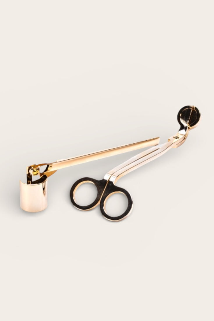 Small pair of candle wick trimmers with gold handle on a light grey background