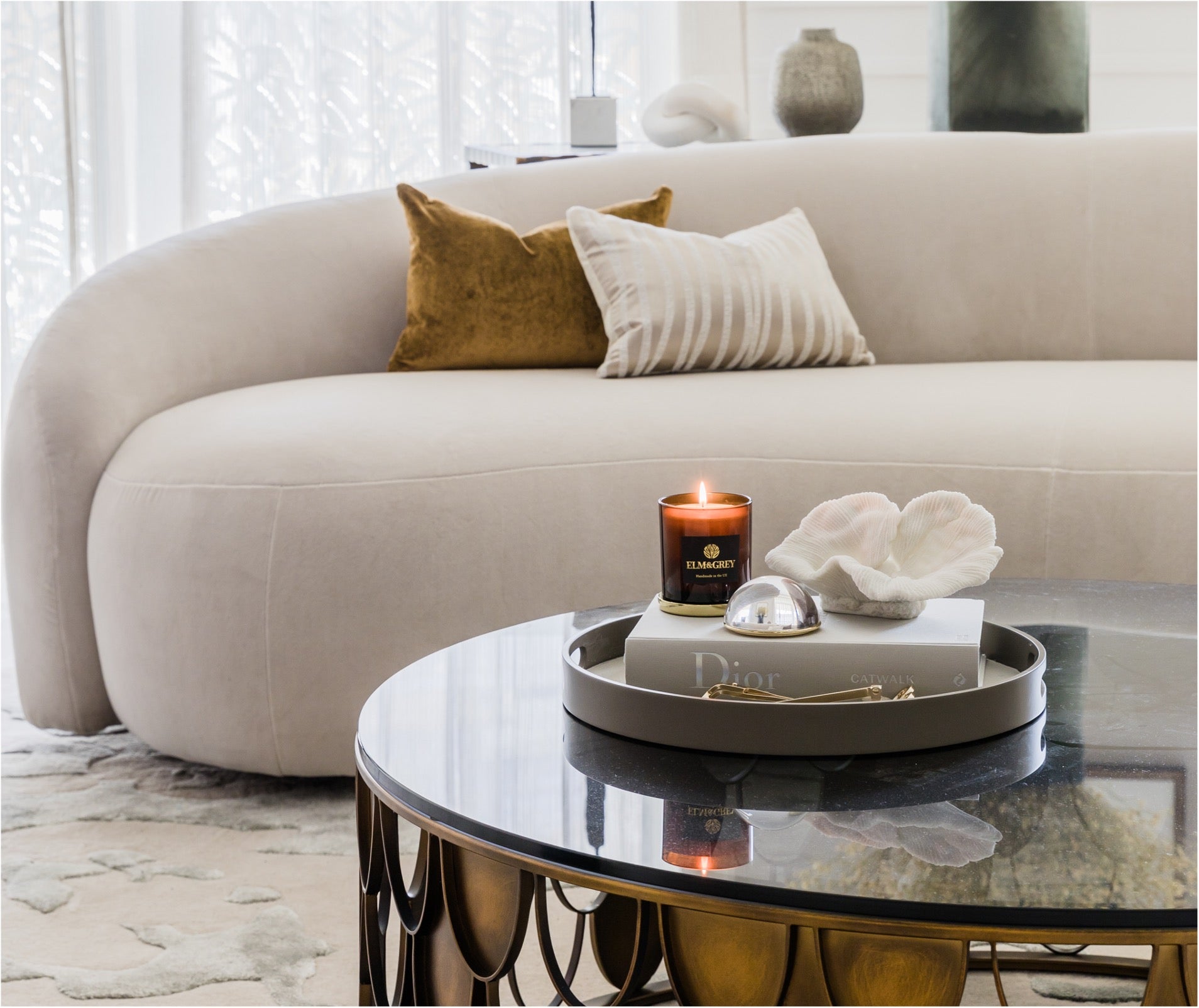 Modern living room with a beige sofa, decorative cushions, and a coffee table with a candle and decor items.