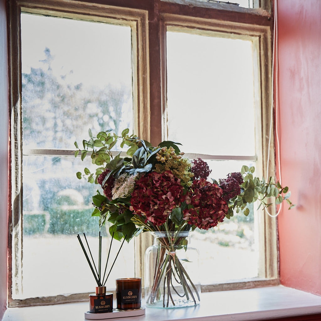 Deluxe Seasonal Hand Tied Bouquet in a windowsill with diffuser and candle from elm and grey on a concrete tray