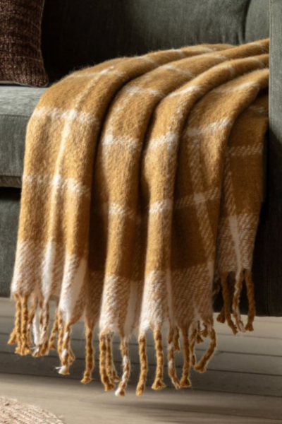 A mustard yellow and white checkered throw blanket draped over a couch, with fringing detail on the edges.