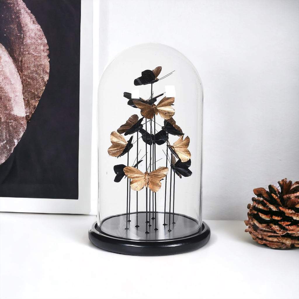 Golden butterflies in a glass dome sitting on a side board 