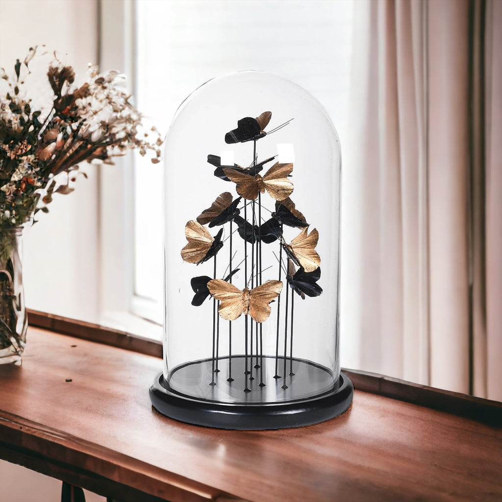 Golden butterflies in a glass dome sitting on a side board 