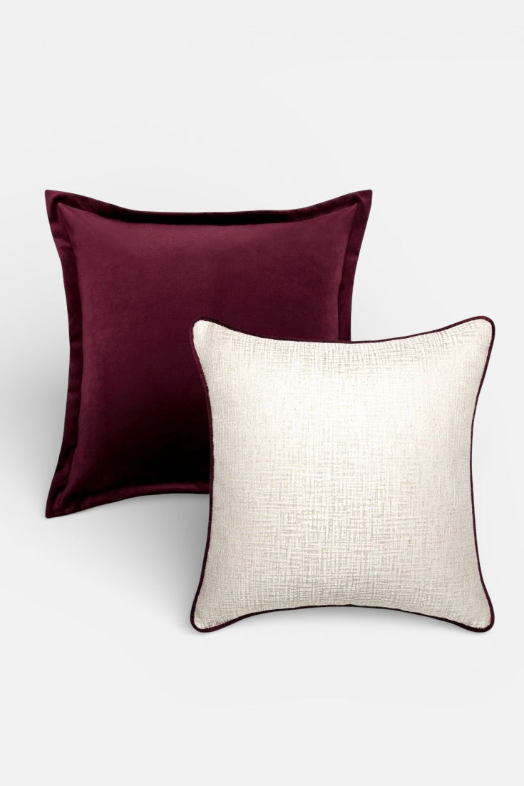 Two cushions, one burgundy and one beige, on a white background