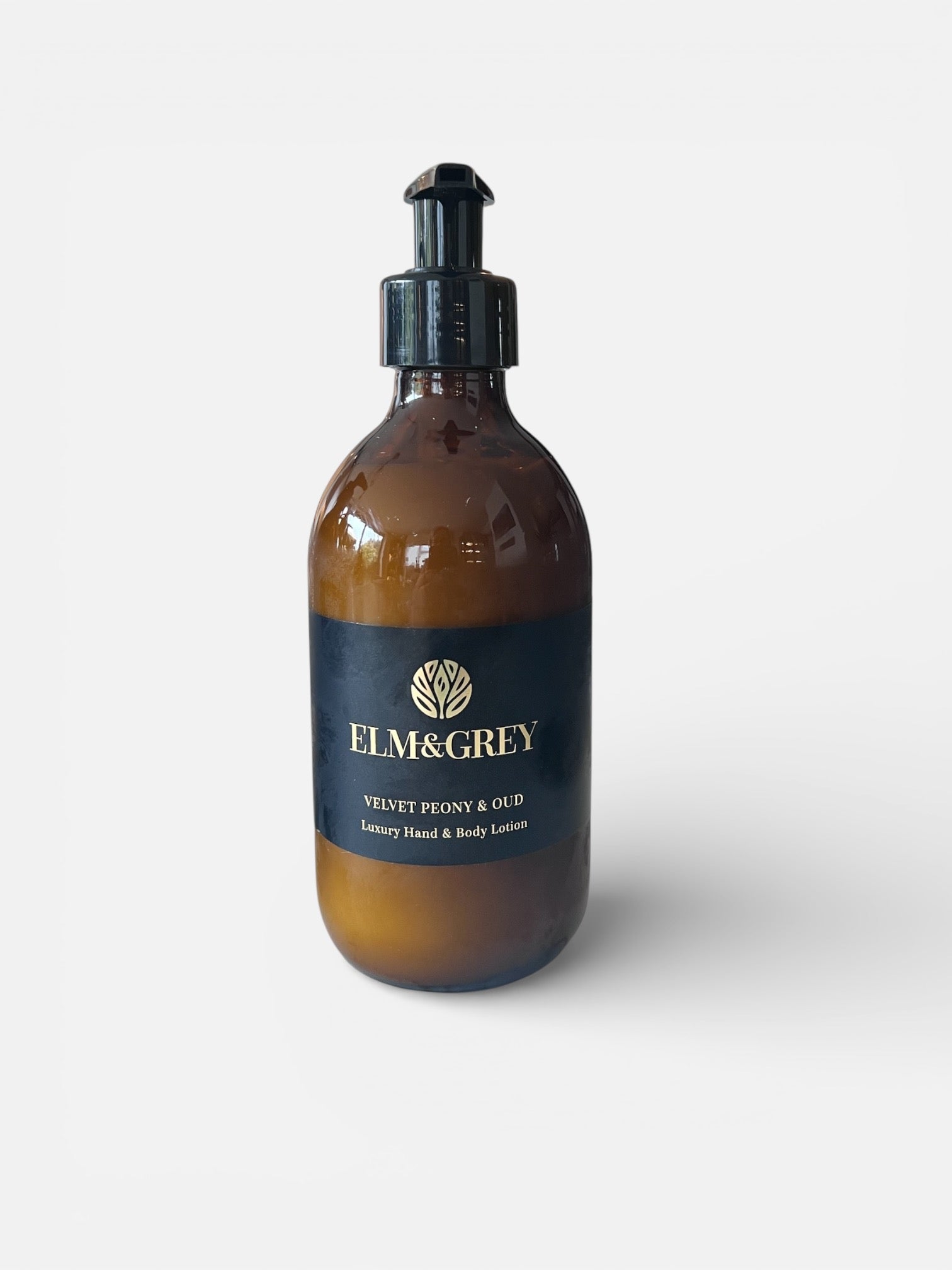 Amber glass bottle with black cap labeled 'Elm&Grey' on a white background