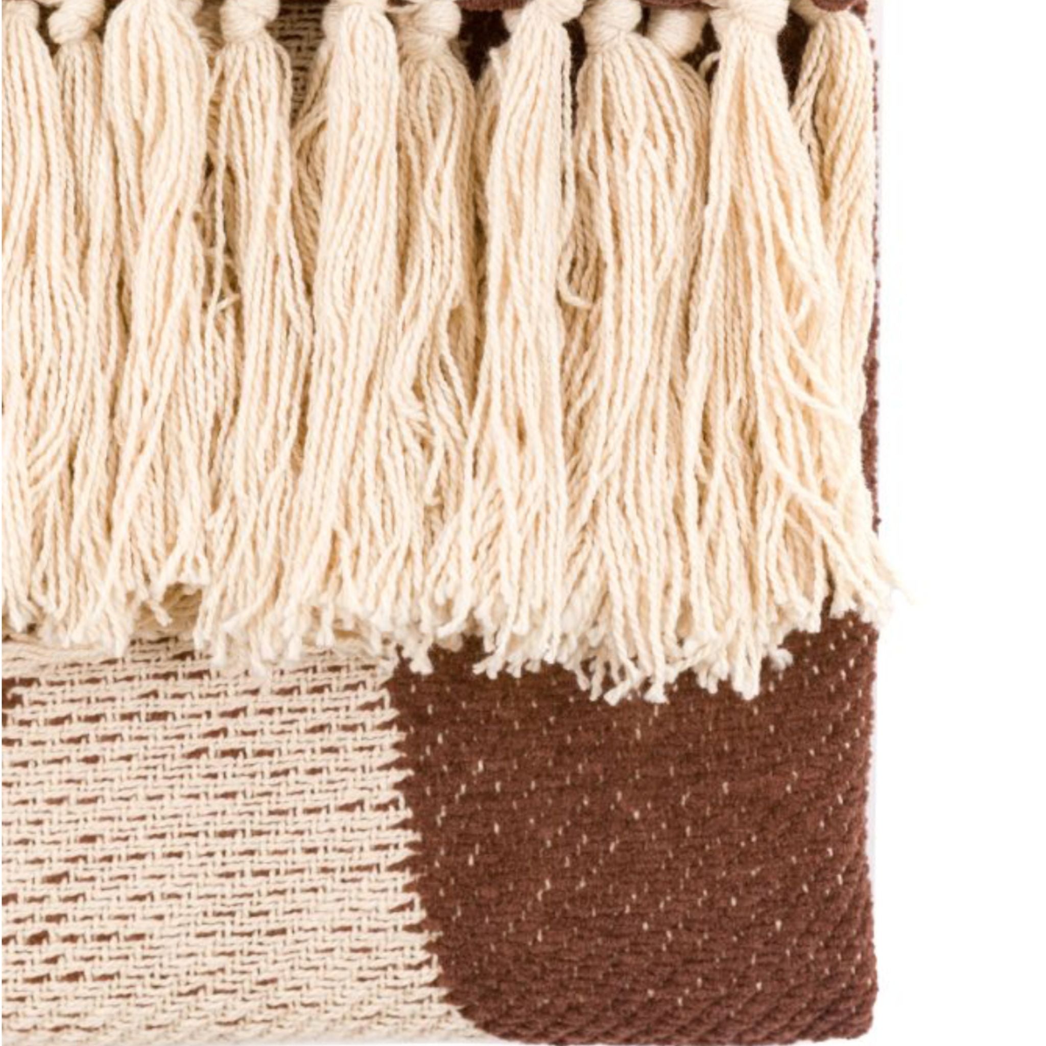 Textile with cream tassels and a brown bottom section on a white background