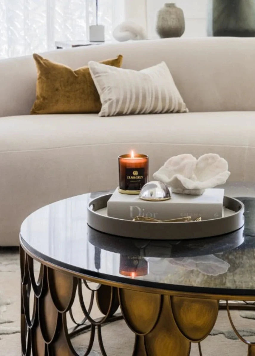 Modern living room with a glass coffee table, candle, and decorative items.
