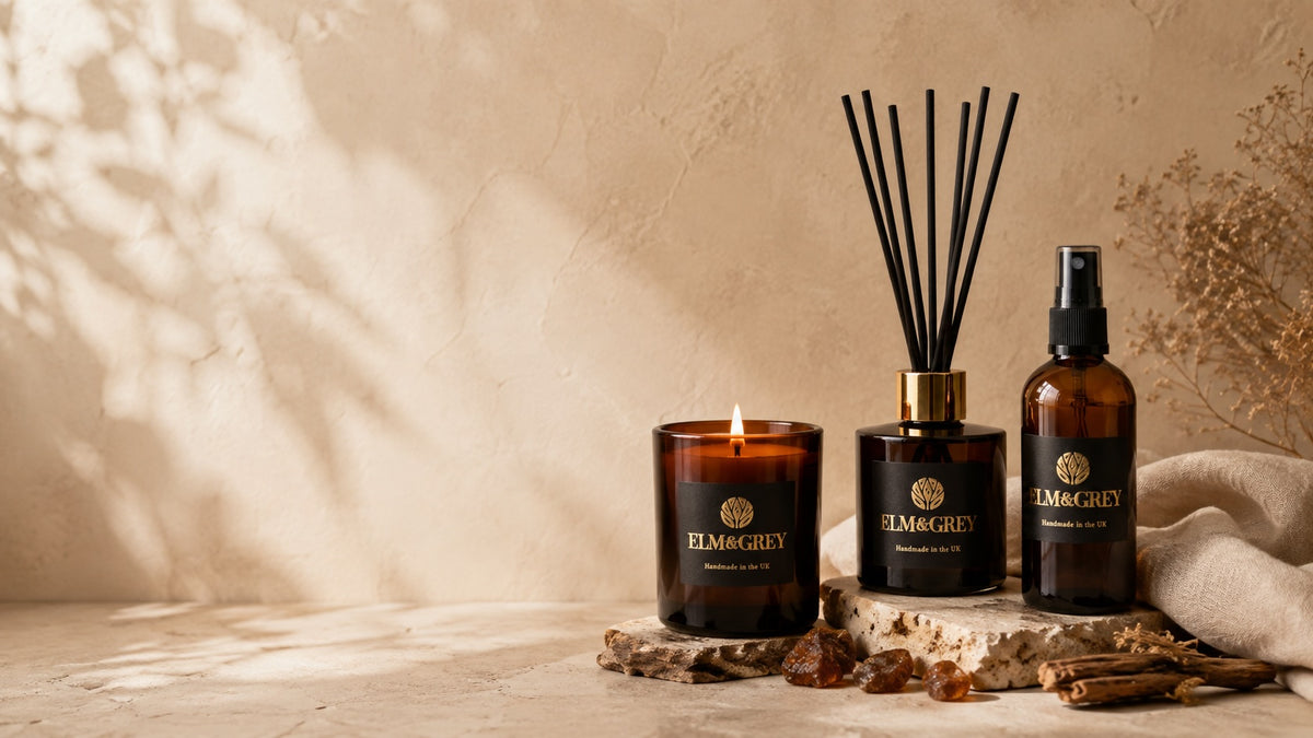 Elm & Grey amber home fragrance collection with lit candle, reed diffuser and room spray in amber glass, styled with warm woods and resins