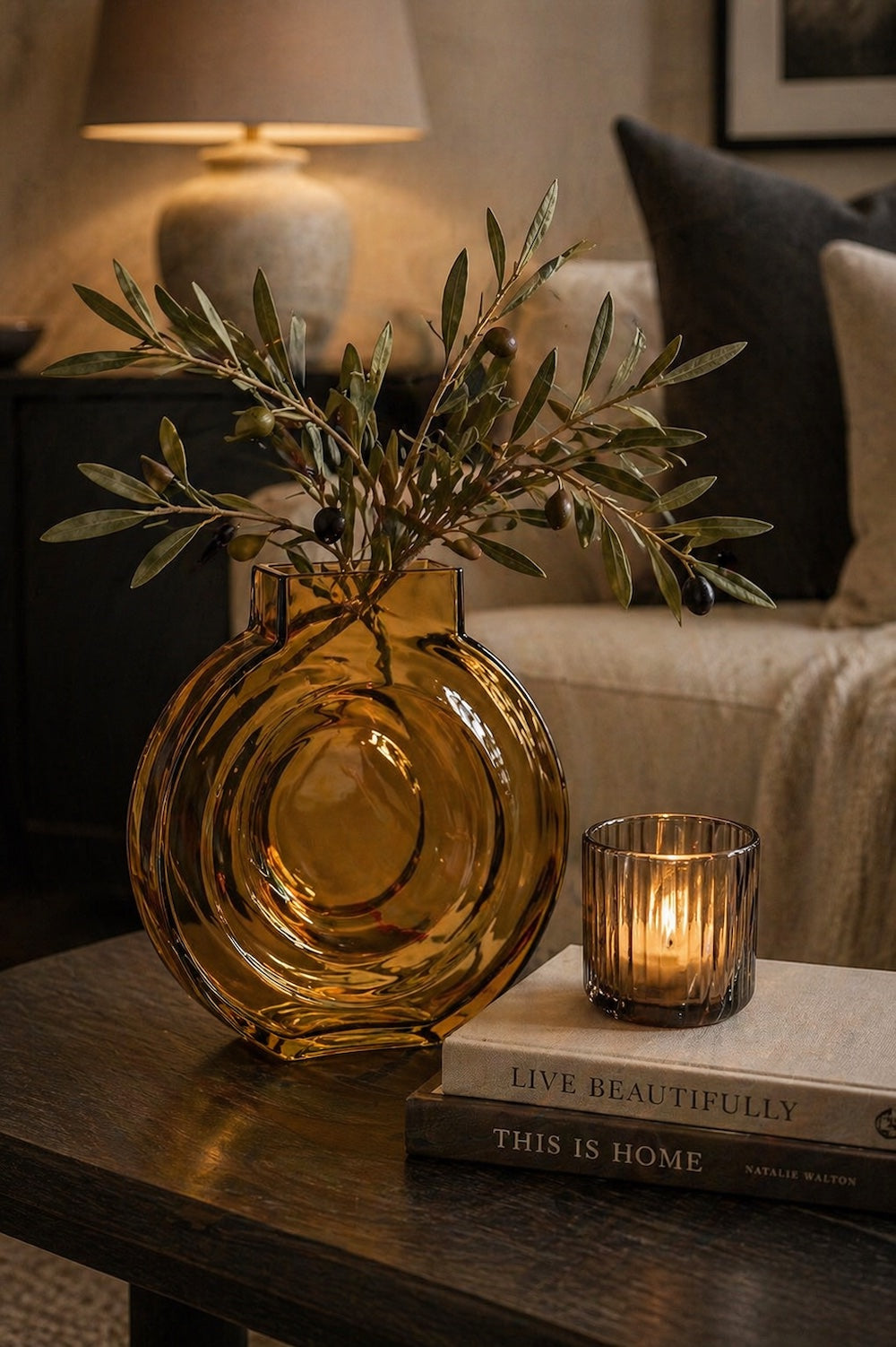 Amber glass moon disc vase with olive branches styled on a dark wood coffee table with lit tealight Elm & Grey