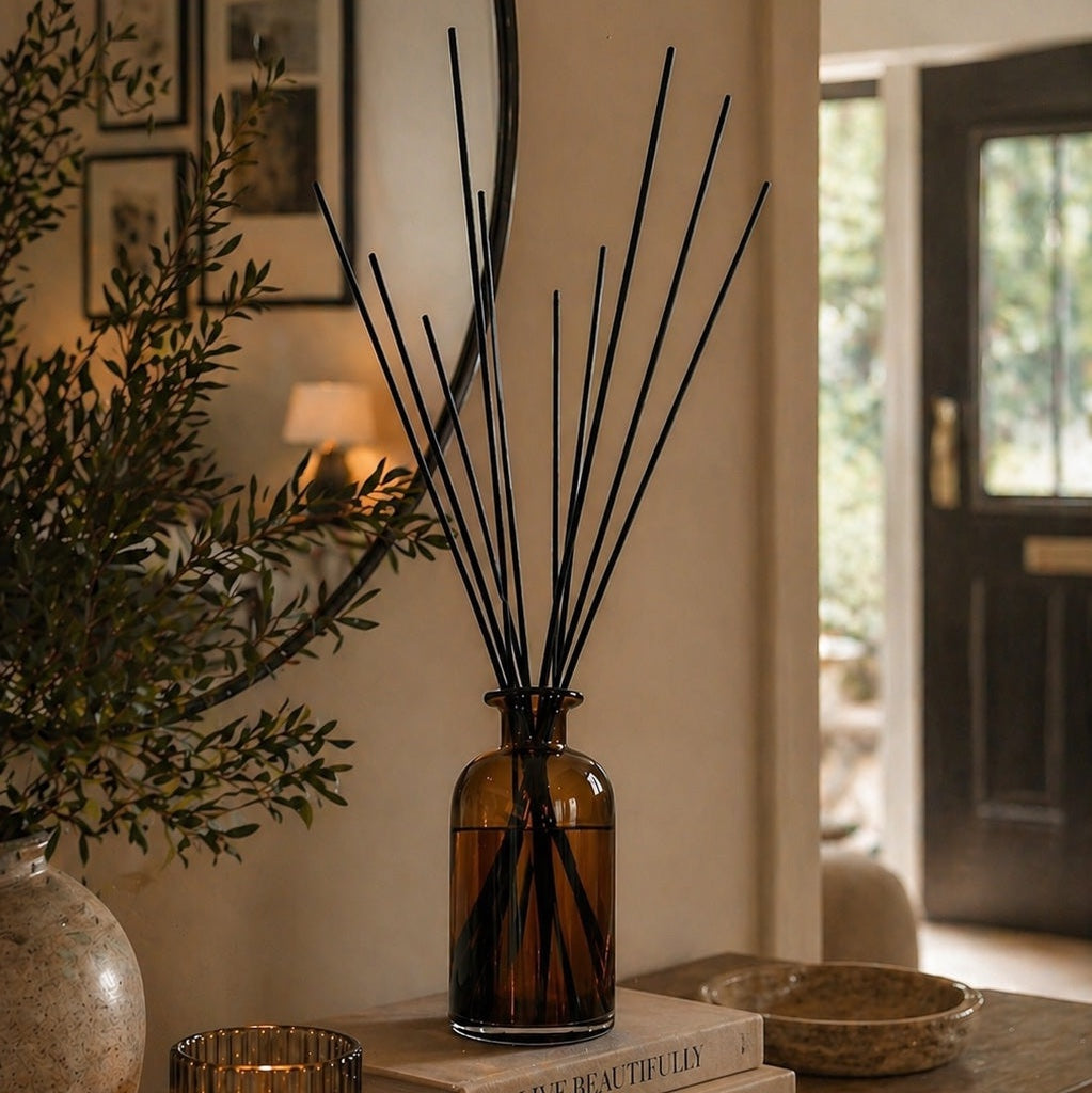 Large amber glass statement reed diffuser with extra-long black reeds on a styled hallway console Elm & Grey