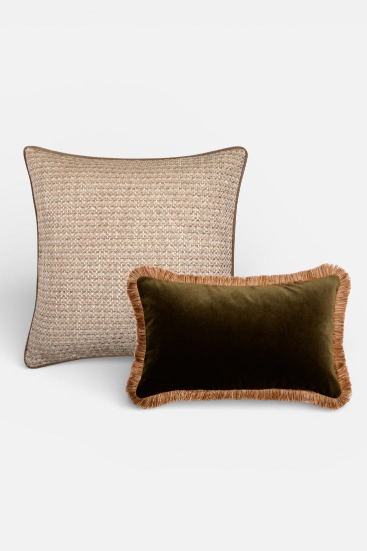 Two decorative cushions, one woven and one velvet with fringe, on a white background.