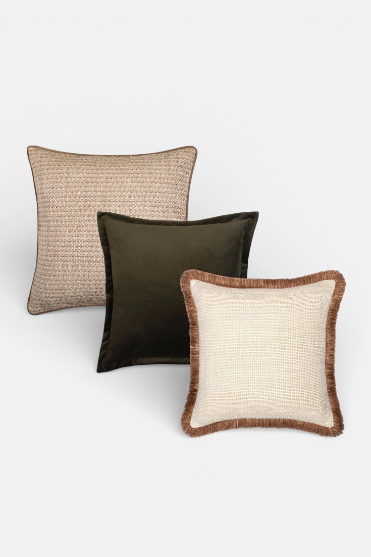 Three decorative pillows in beige, deep juniper green, and white on a white background