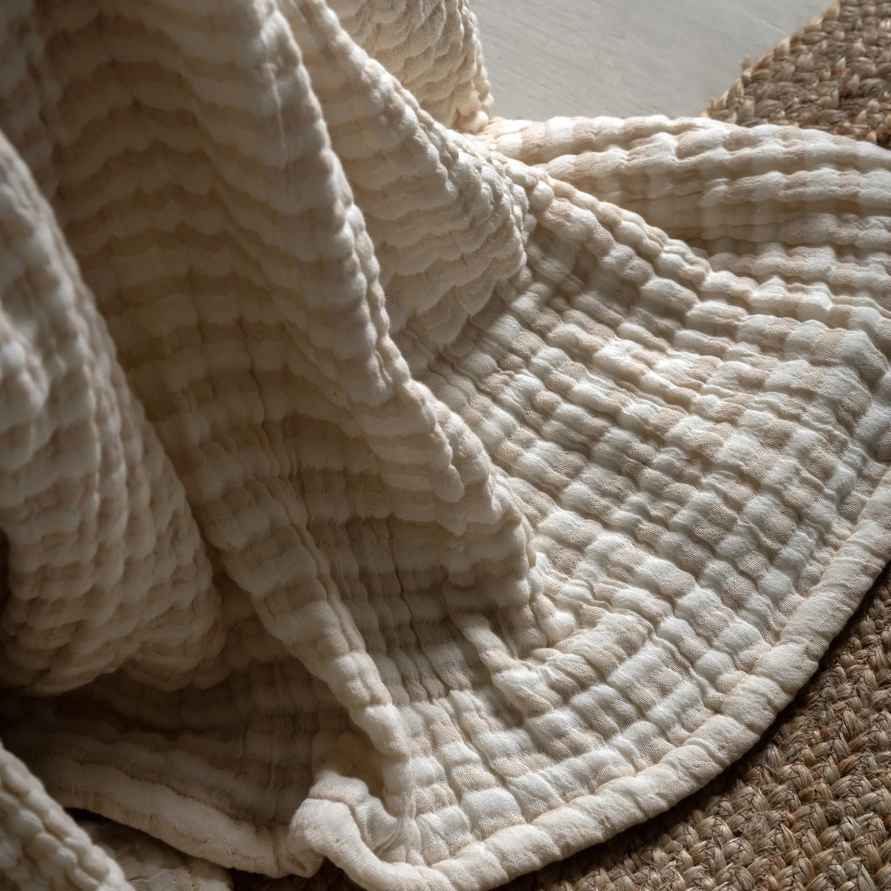 Close-up of a textured beige bedspread on a wooden surface