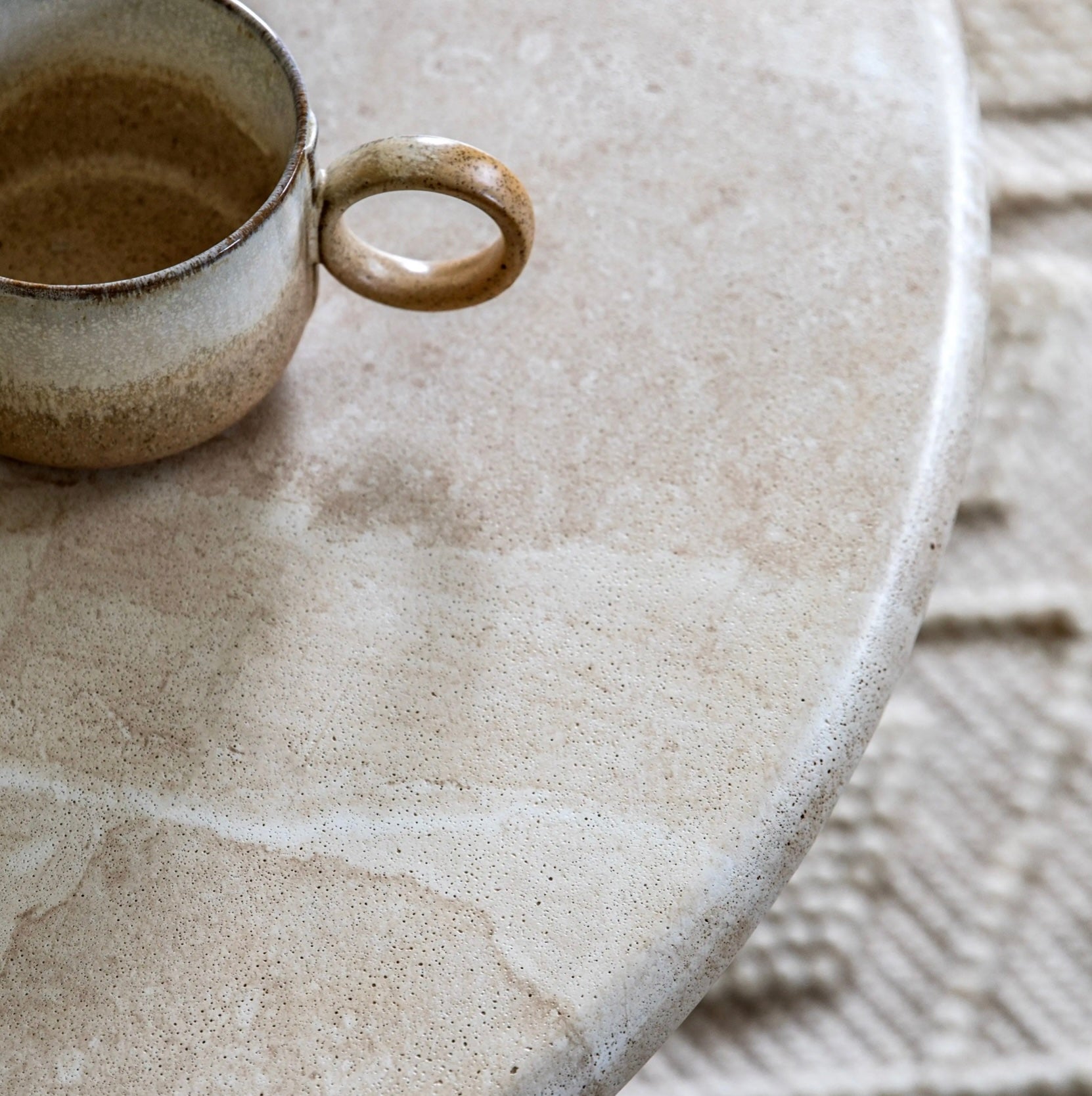 Ceramic cup on travertine effect coffee table with a rug in the background