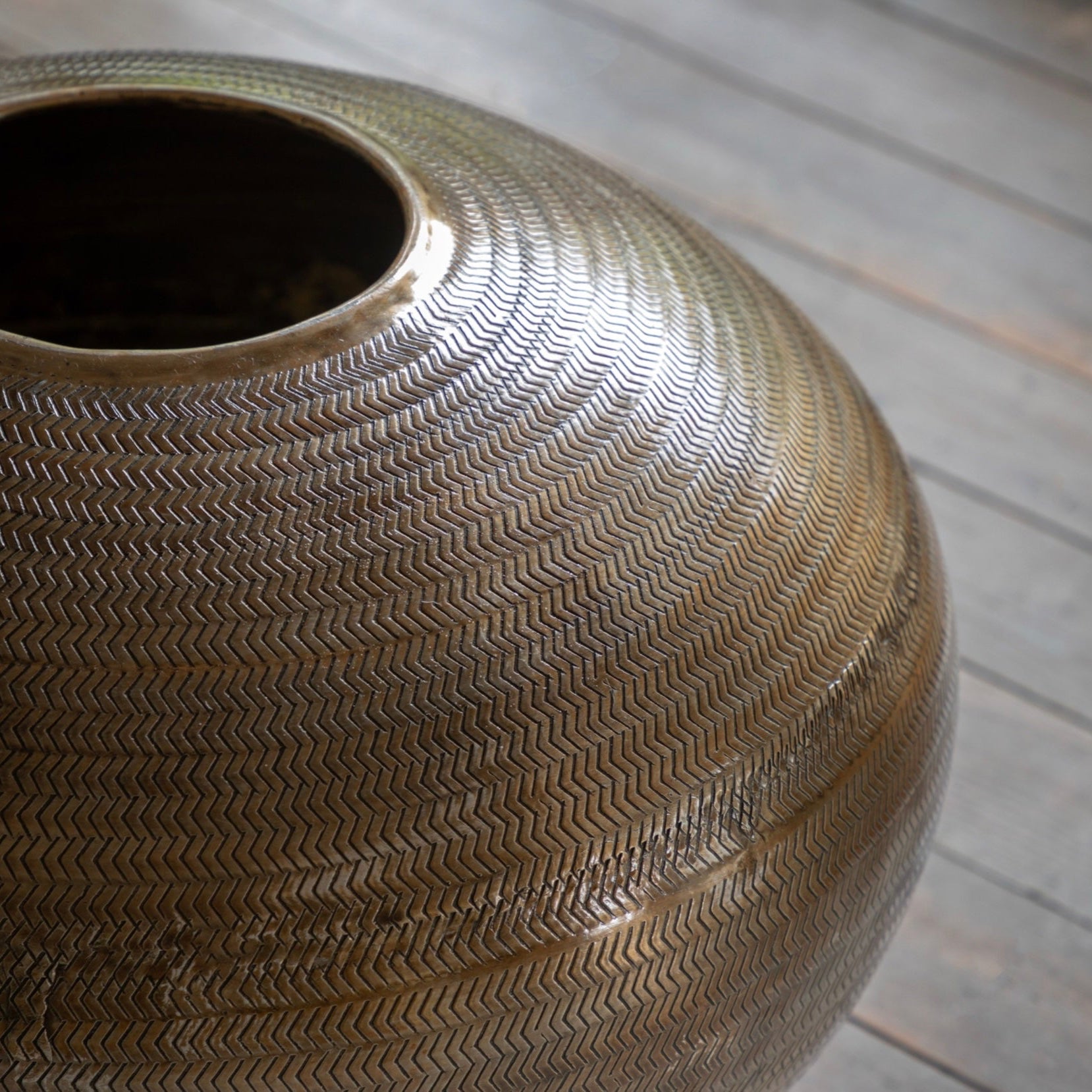 Textured antiqued brass vase on a wooden surface