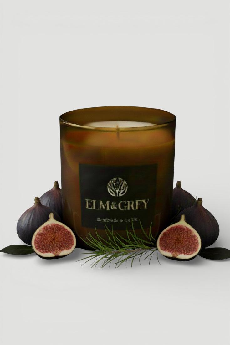 Candle with 'ELM & GReY' branding surrounded by figs on a light background