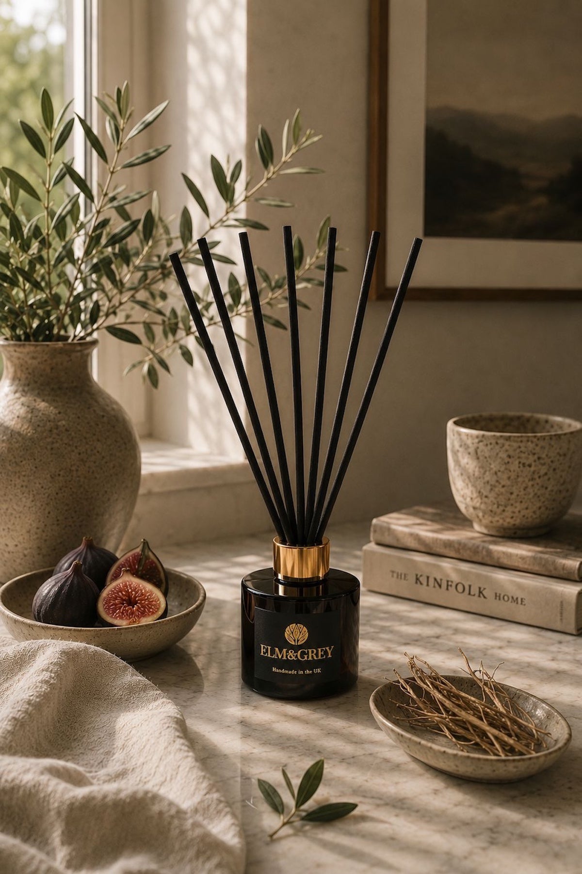 Black Fig & Vetiver luxury reed diffuser by Elm & Grey styled with fresh figs, olive branches and natural stone textures in a calm contemporary interior.