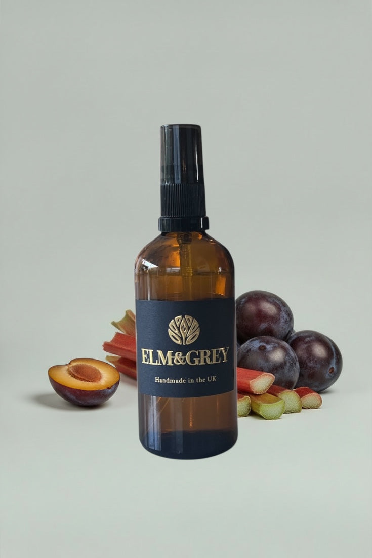 Bottle of Elm & Grey product with plums and apricots on a light grey background