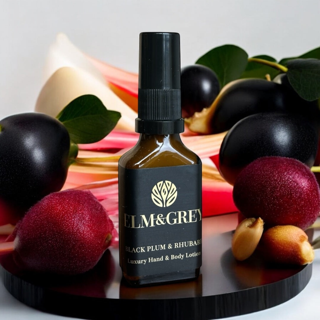 Bottle of Elm & Grey Black Plum & Rhubarb luxury hand and body lotion surrounded by fruits on a dark surface.
