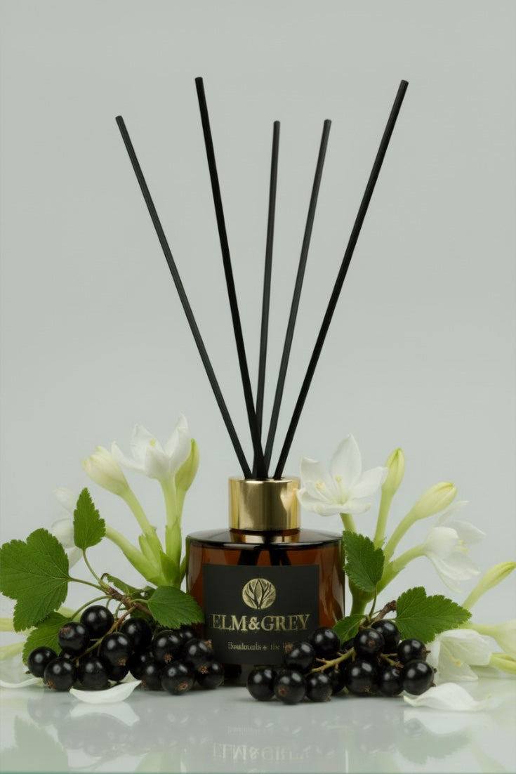 Reed diffuser with black sticks and decorative elements on a light grey background