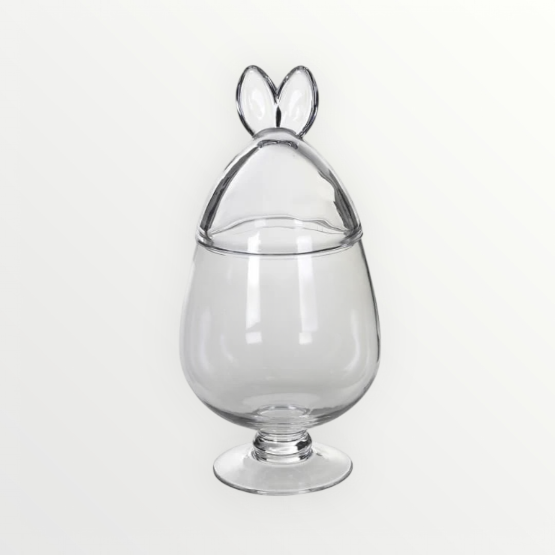 A clear glass jar with a unique rabbit ears lid on a white background.