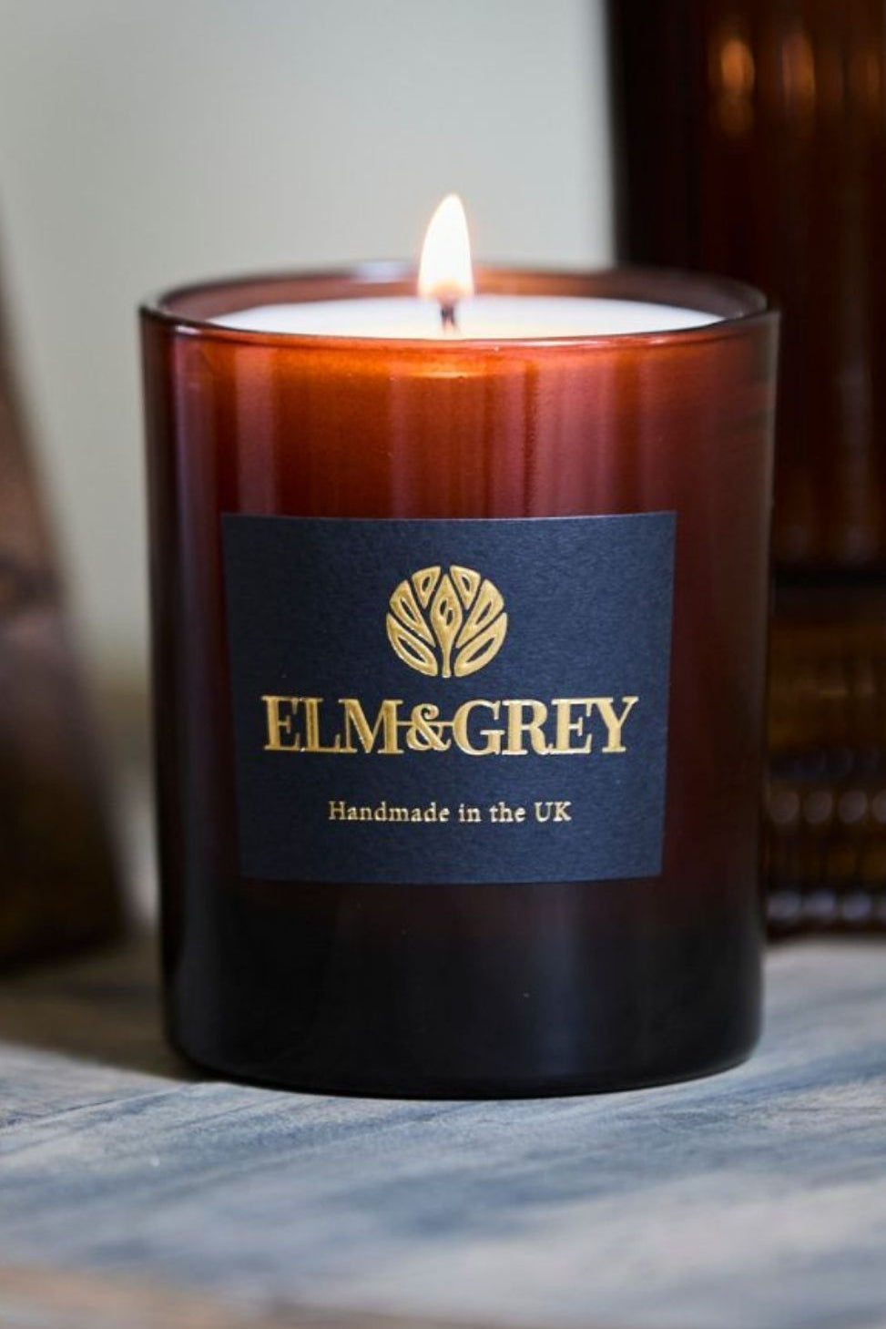 Candle with Elm & Grey label on a wooden surface