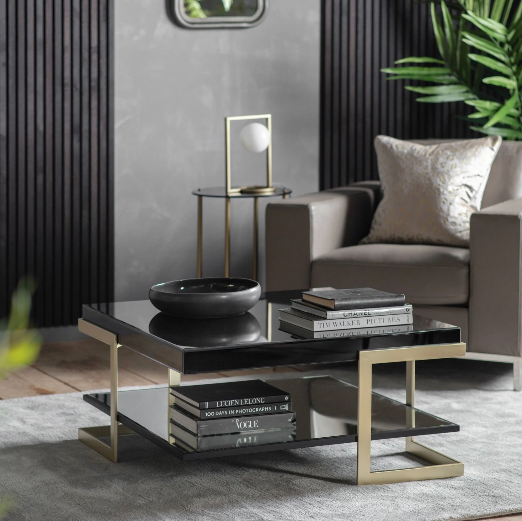 Modern living room with a black coffee table, books, and a gray sofa.