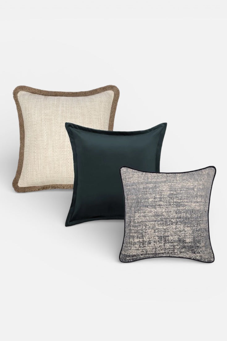 Three textured pillows in beige, black, and gray on a white background