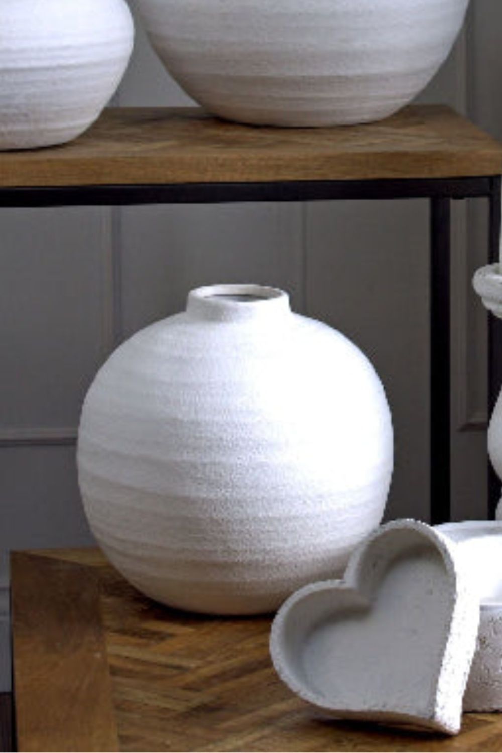 White ceramic vase on a wooden surface with a neutral background