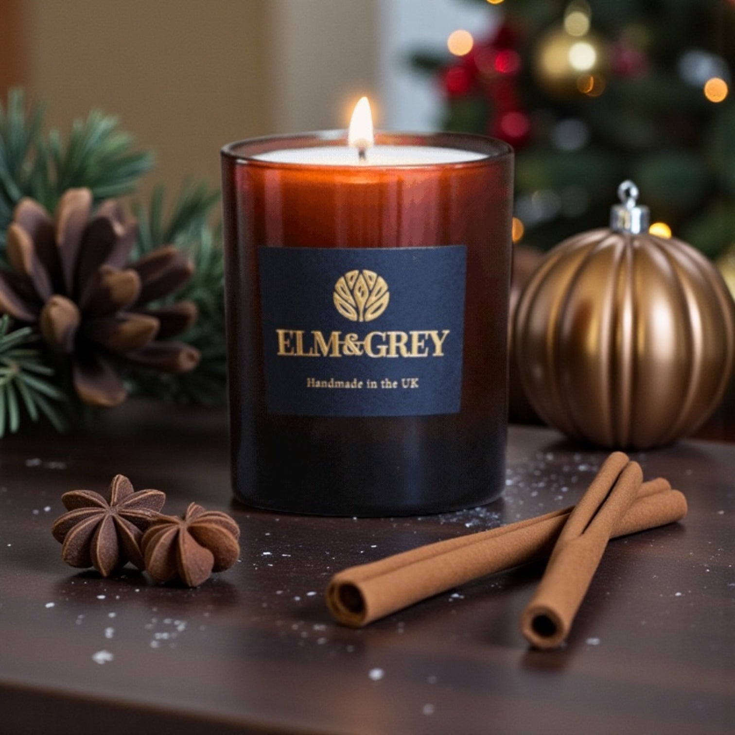 Elm & Grey candle with Christmas decorations on a dark surface