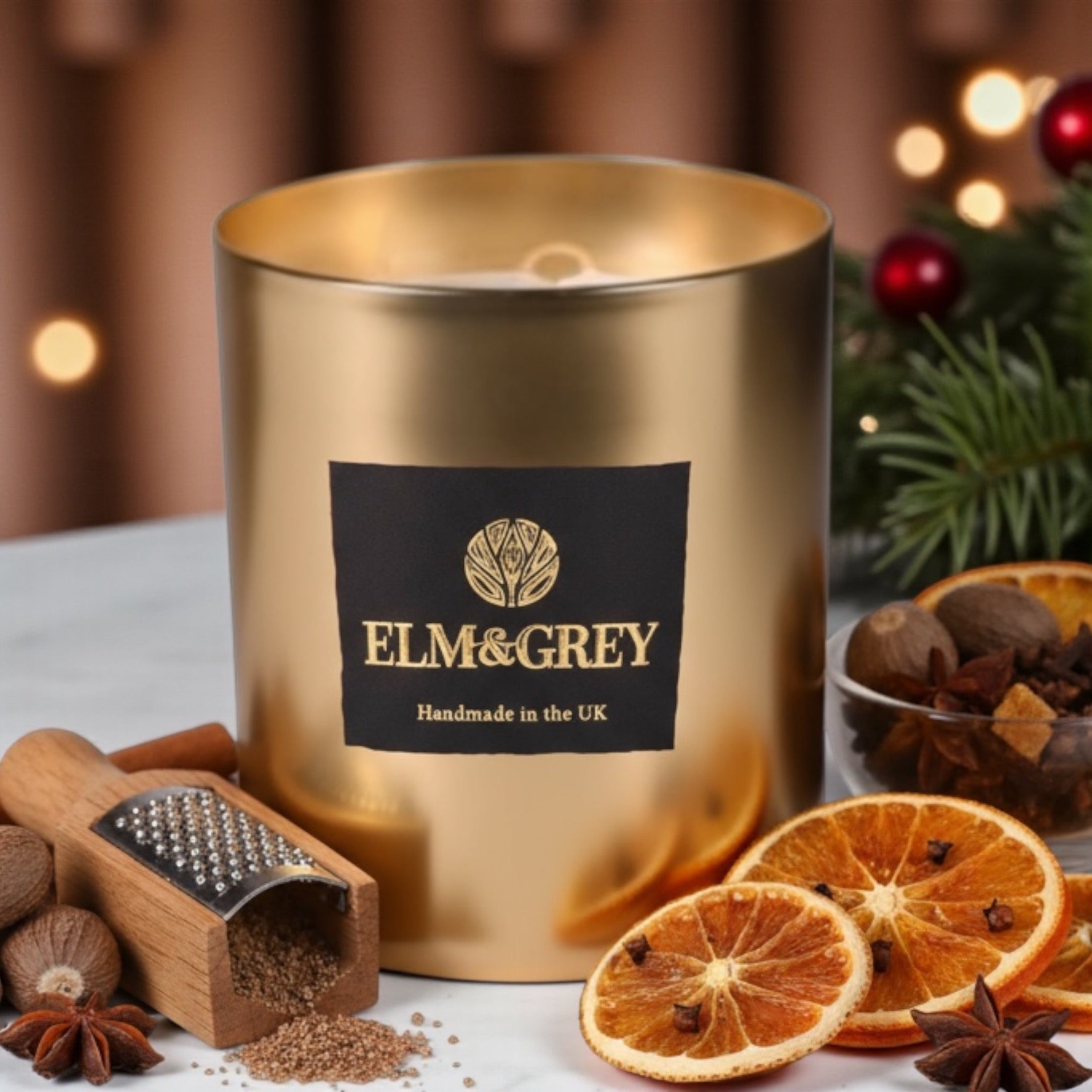 Gold candle with Elm & Grey label surrounded by spices and oranges on a festive background