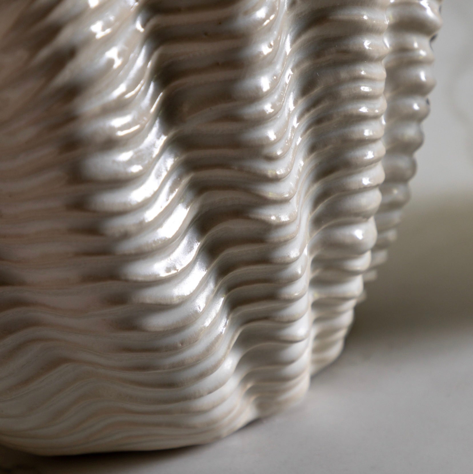 Close-up of a textured ceramic clam vase with wavy pattern on a neutral background