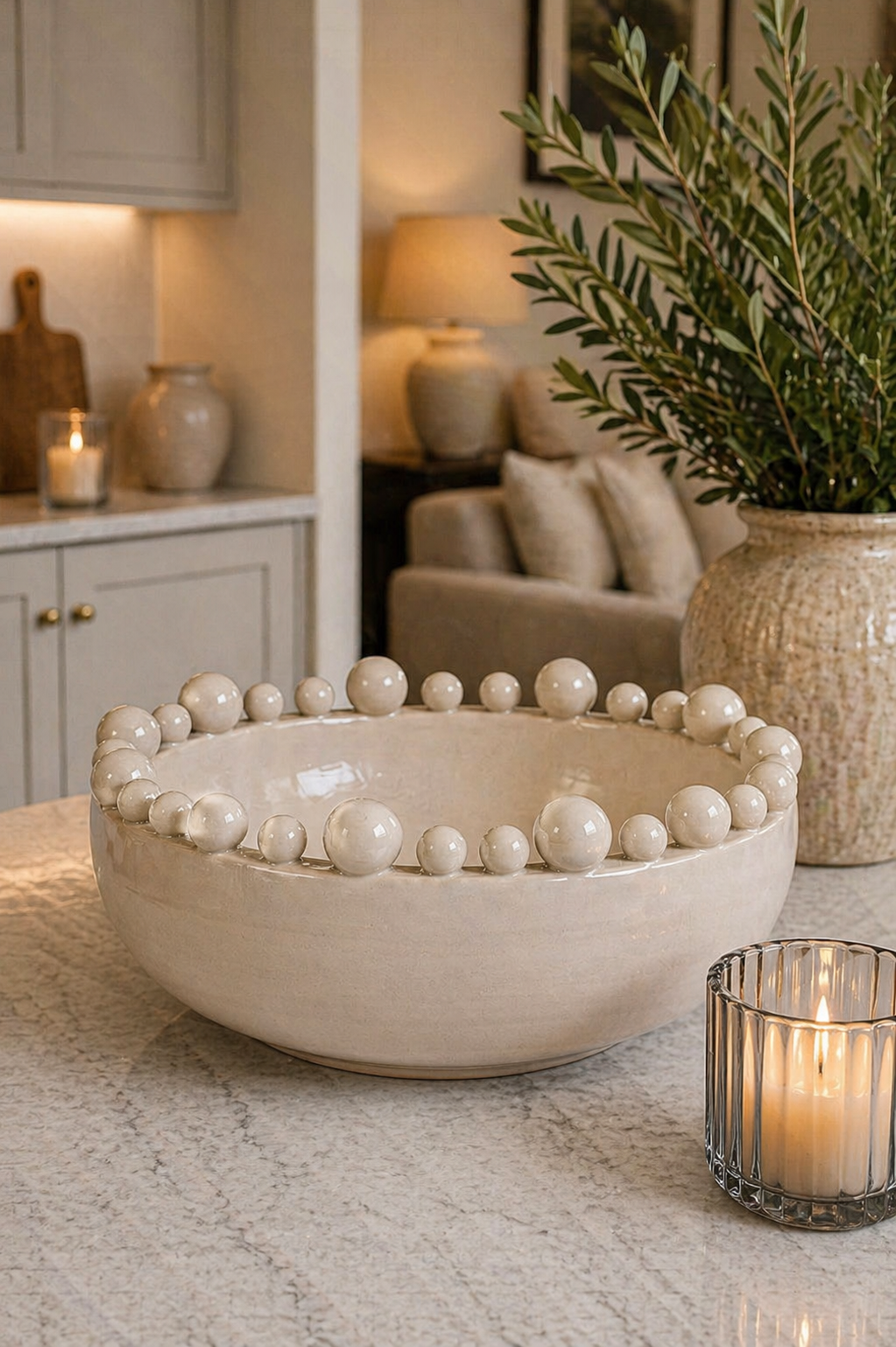 Decorative bowl with spherical embellishments on a table with candles and plants.