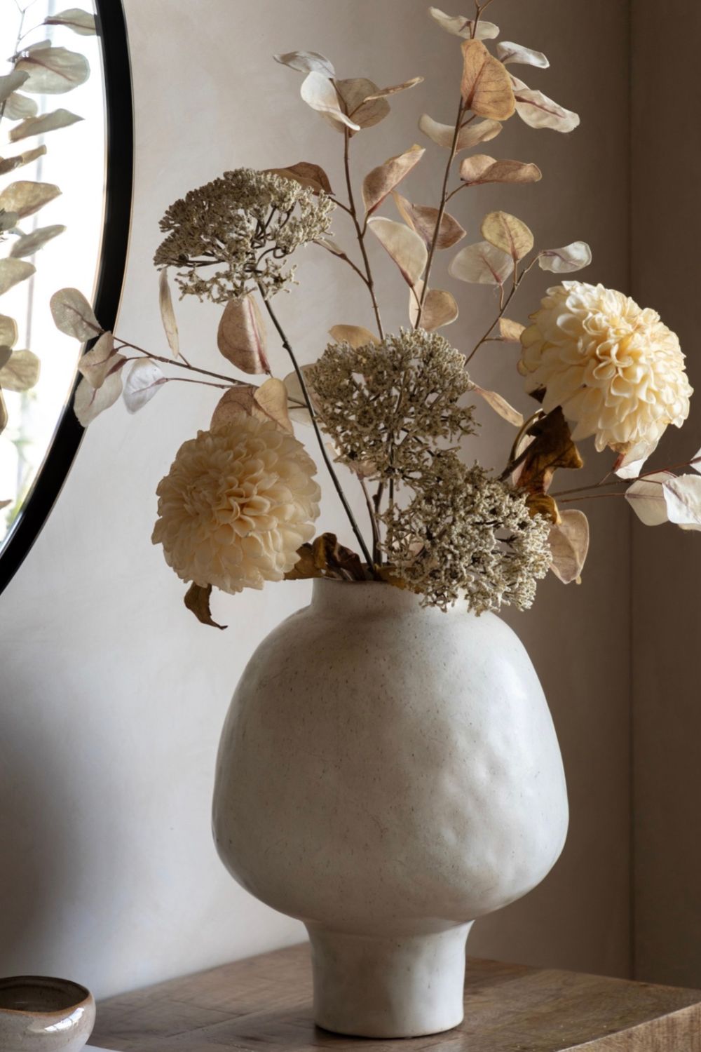 Ceramic vase with dried flowers on a wooden surface