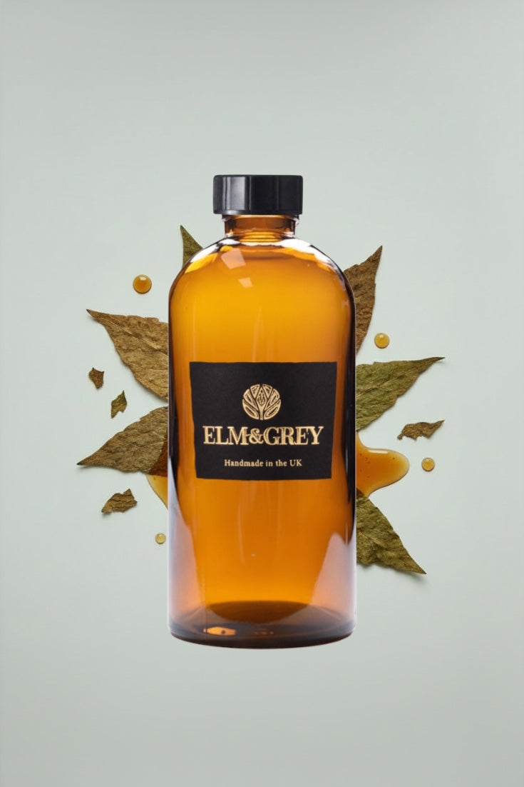 Bottle of Elm & Grey diffuser refill liquid with leaves on a light background