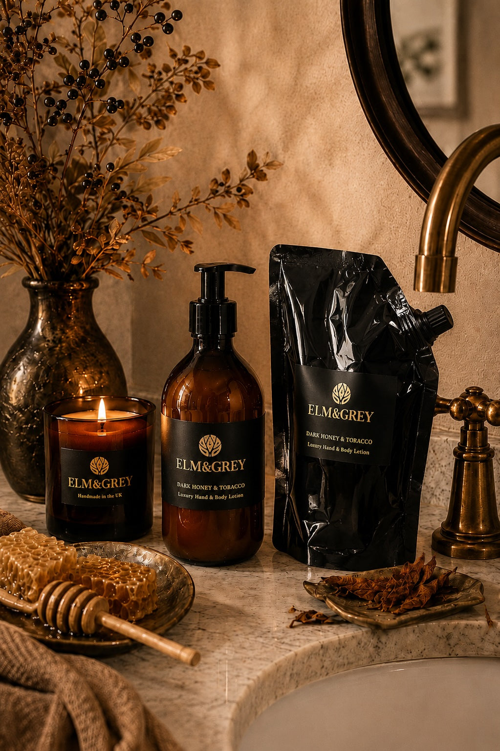 Bathroom counter with Elm and Grey dark honey and tobacco fragranced products including a candle, hand and body wash and refill.
