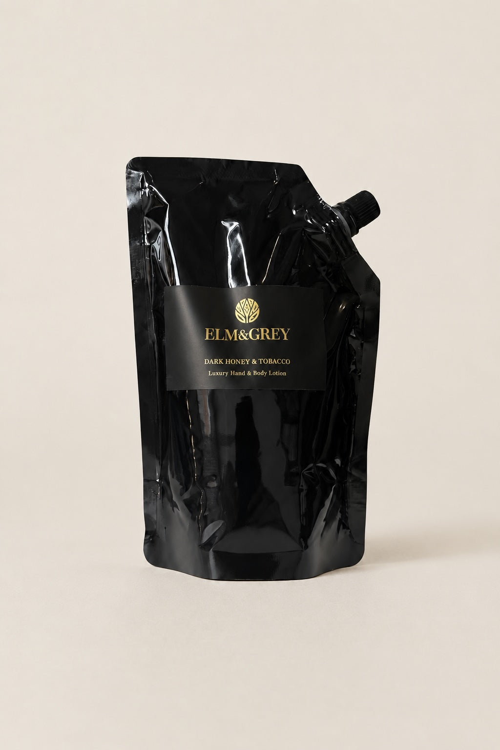 Elm & Grey Dark Honey & Tobacco hand and body lotion refill pouch on a neutral studio background
