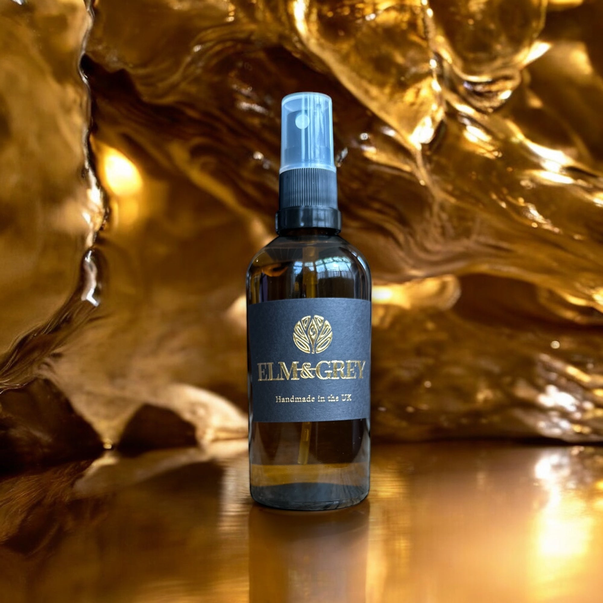 Bottle of Elm & Grey product on a reflective surface with a textured gold background