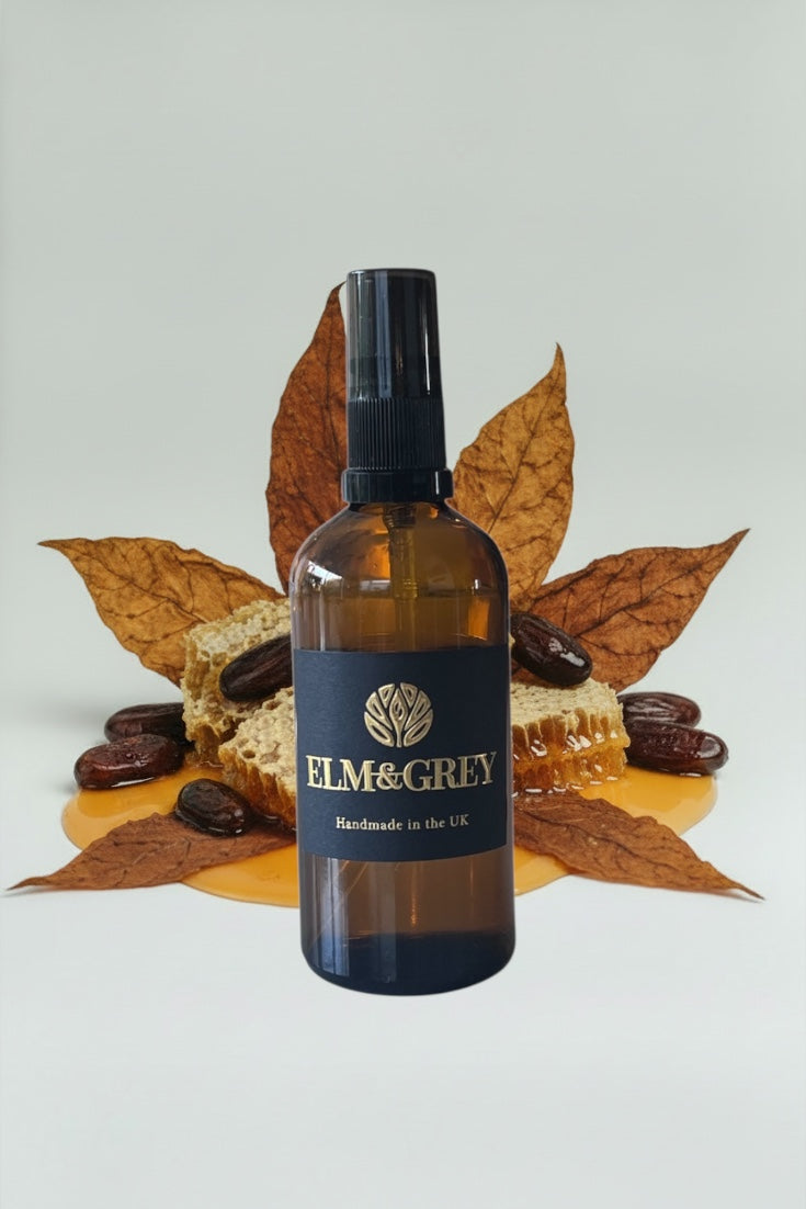 Bottle of Elm & Grey product with honeycomb and leaves on a light background