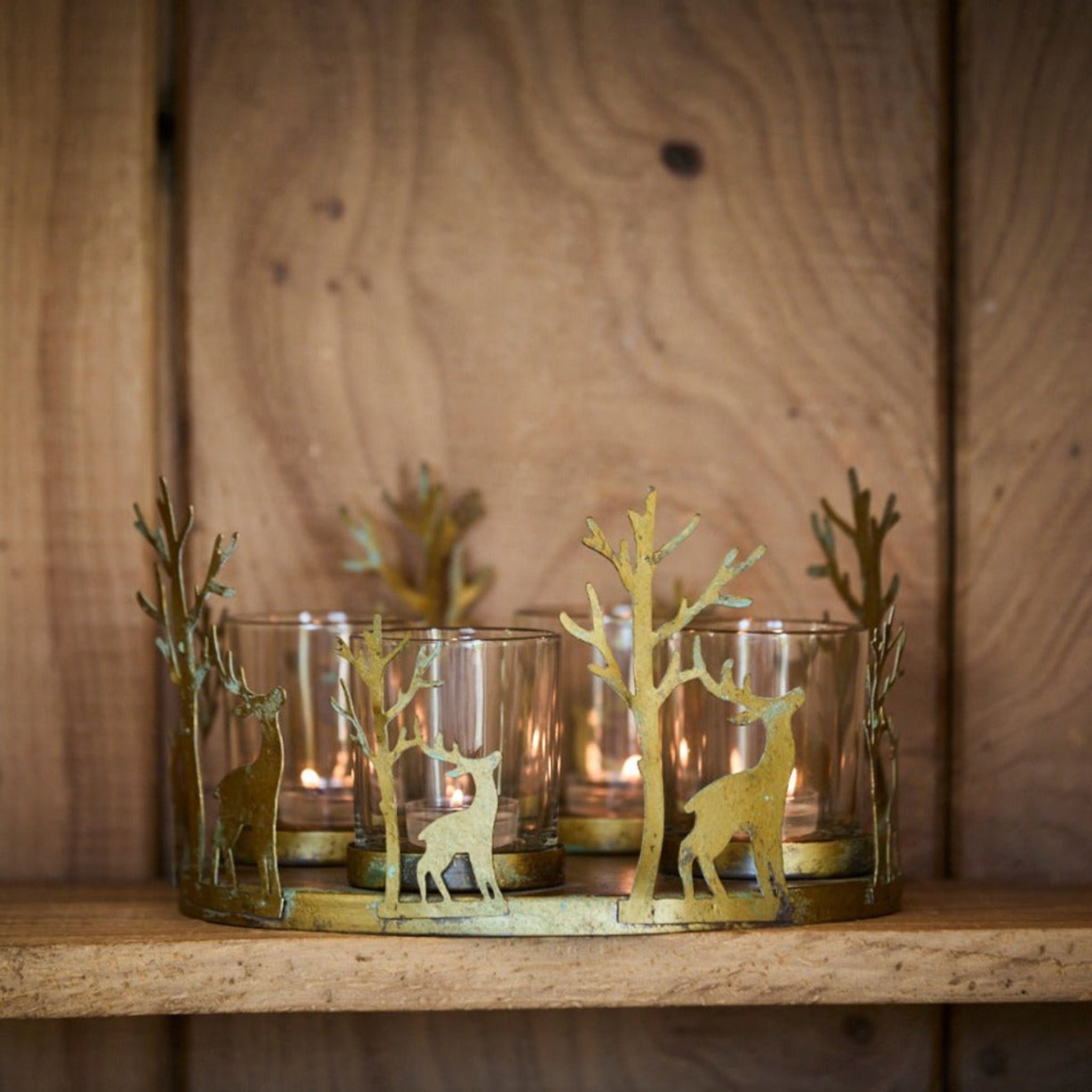 Decorative candle holders with deer silhouettes on a wooden surface.