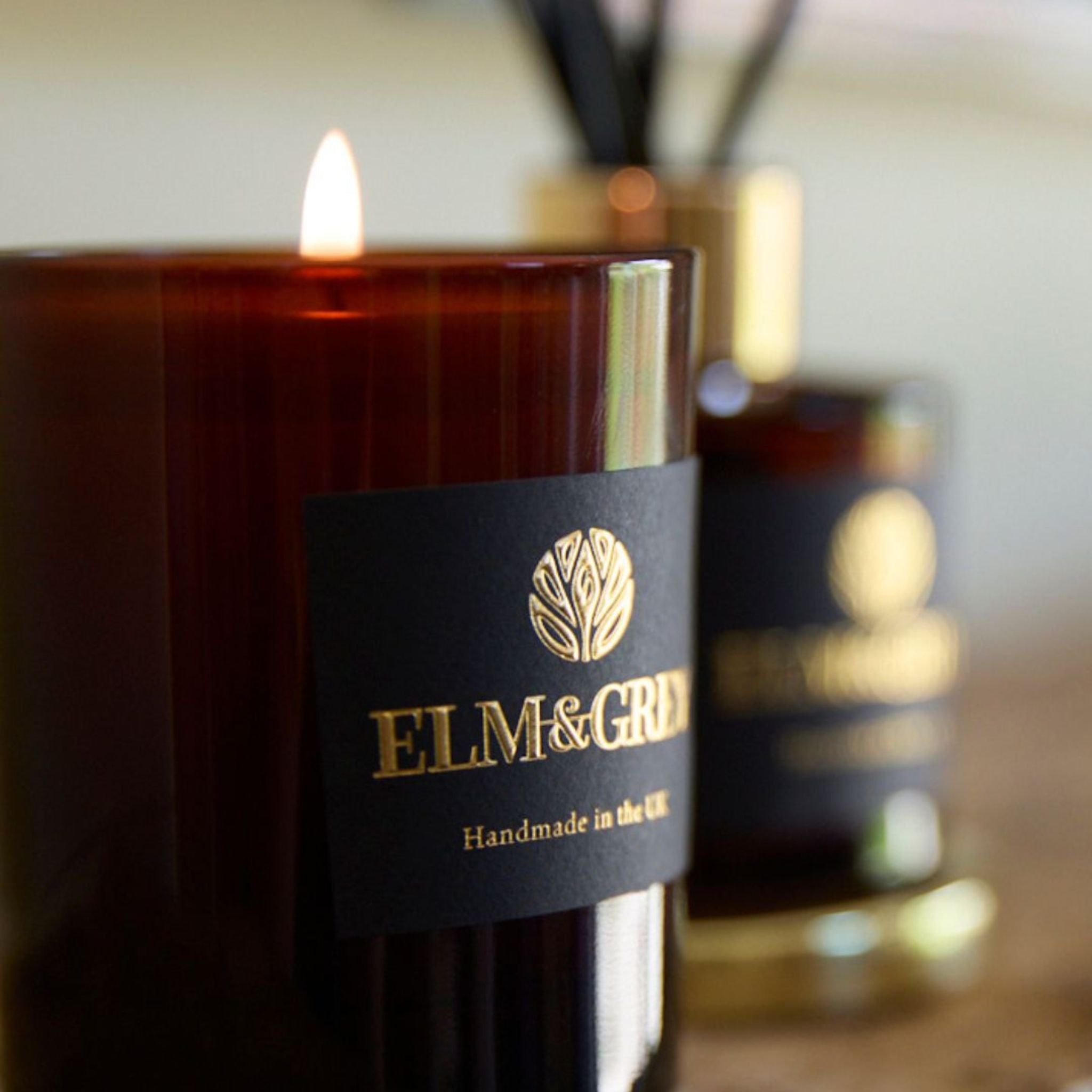 Candle with 'ELM & GREY' label on a blurred background