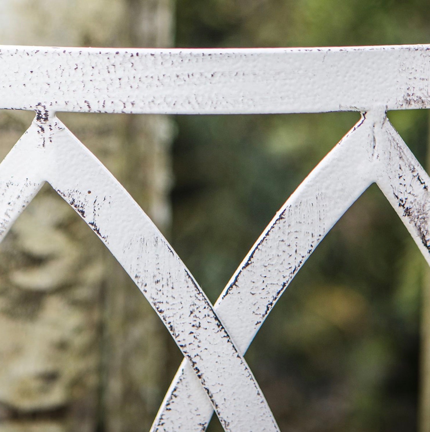 Close-up of a white metal lattice structure with a blurred natural background