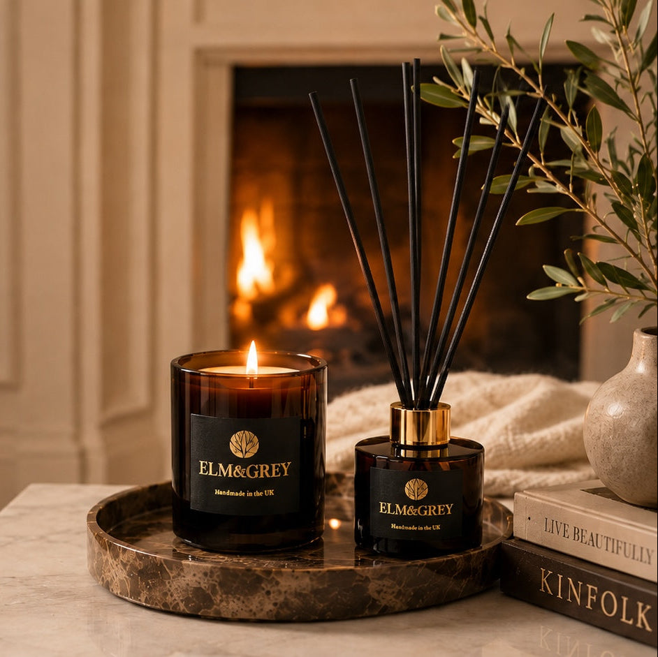 Luxury Elm & Grey amber candle and reed diffuser styled by a fireplace for a warm, calming home fragrance ritual
